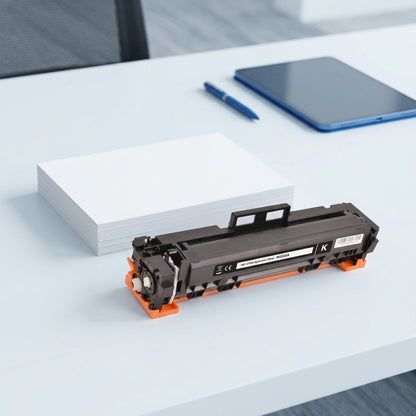 HP 215A compatible black toner cartridge next to a stack of paper and a tablet for scale reference.