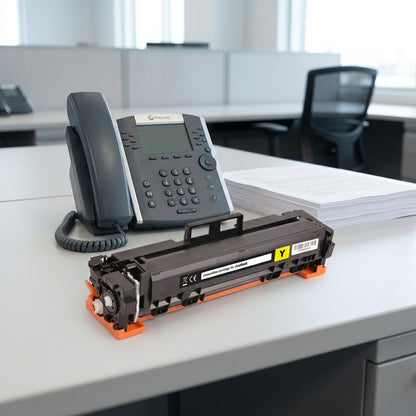 HP 414A W2022A yellow toner cartridge on a desk next to an office phone and paper for scale.