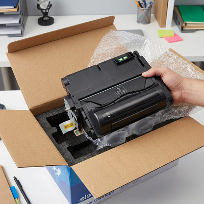 A black HP 42X (Q5942X) compatible toner cartridge being unboxed from protective foam and bubble wrap.