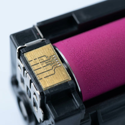 Macro detail of a magenta toner cartridge showing the gold contact chip and developer roller.