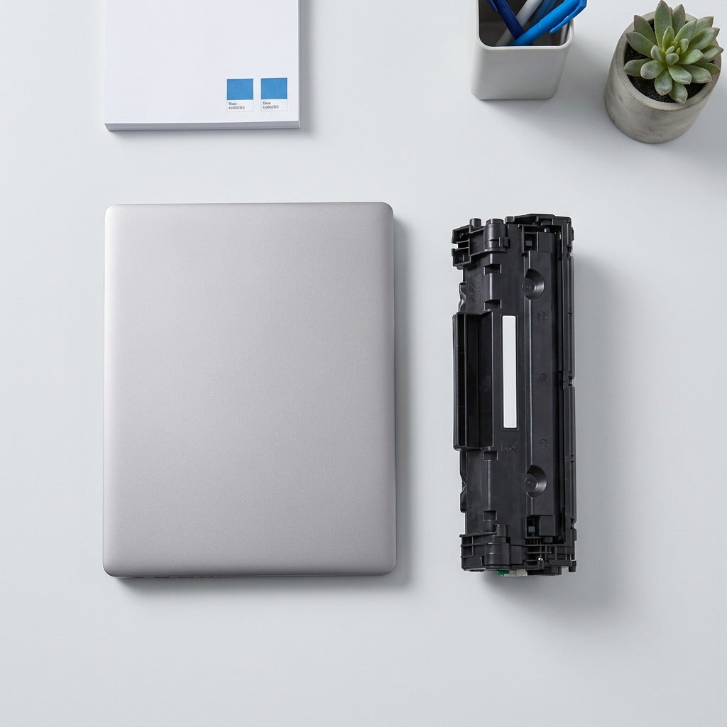 Scale reference of a black HP 645A C97311A cyan toner cartridge next to a 14-inch laptop.