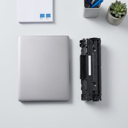 Scale reference of a black HP 645A C97311A cyan toner cartridge next to a 14-inch laptop.