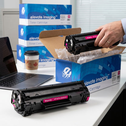 A hand unboxing a Magenta HP 647A (CB383A) remanufactured toner cartridge by Elevate Imaging.