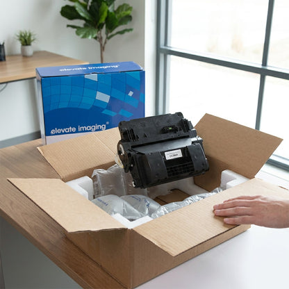 An Elevate Imaging CC364A black toner cartridge unboxed with protective air pillows and foam.