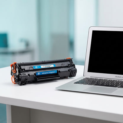 Elevate Imaging HP 648A (CE261A) cyan toner cartridge on a white desk next to a laptop for scale.
