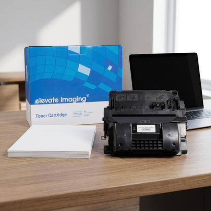Elevate Imaging HP CE390X toner cartridge on an office desk next to a laptop and paper stack.