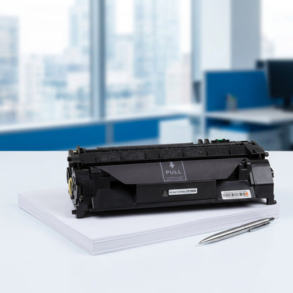Matte black HP 80A (CF280A) compatible toner cartridge on a stack of white paper with a silver pen.