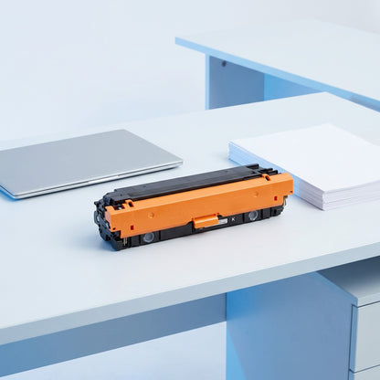 Elevate Imaging HP 508X toner cartridge on an office desk next to a laptop and paper for scale.