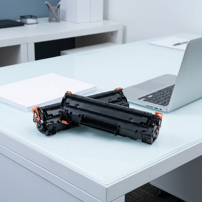Elevate Imaging HP 312A magenta toner cartridge on a desk next to a laptop for scale reference.