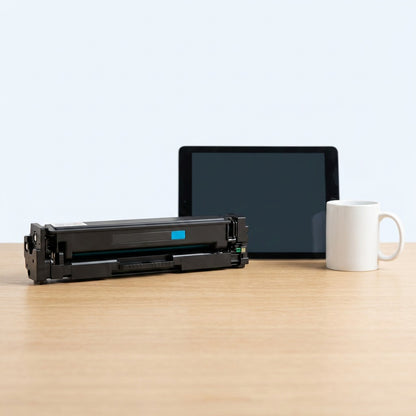HP 201X cyan toner cartridge shown for scale on a desk next to a digital tablet and coffee mug.