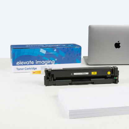 Elevate Imaging yellow toner cartridge for HP 201A beside a laptop and paper stack for scale.