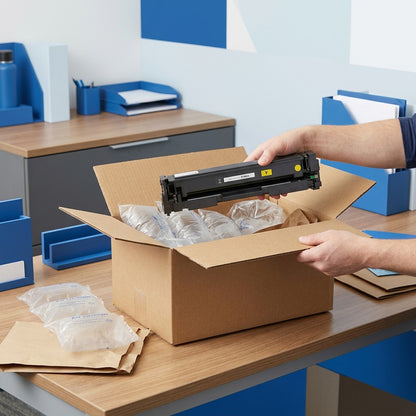 Unboxing a yellow HP 201A compatible toner cartridge from a shipping box with protective air cushions.