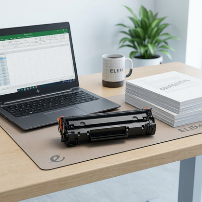 Elevate Imaging HP 654X Black Toner Cartridge shown on a desk next to a laptop for scale reference.