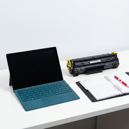Yellow HP 202X toner cartridge on a desk next to a tablet and planner for scale reference.